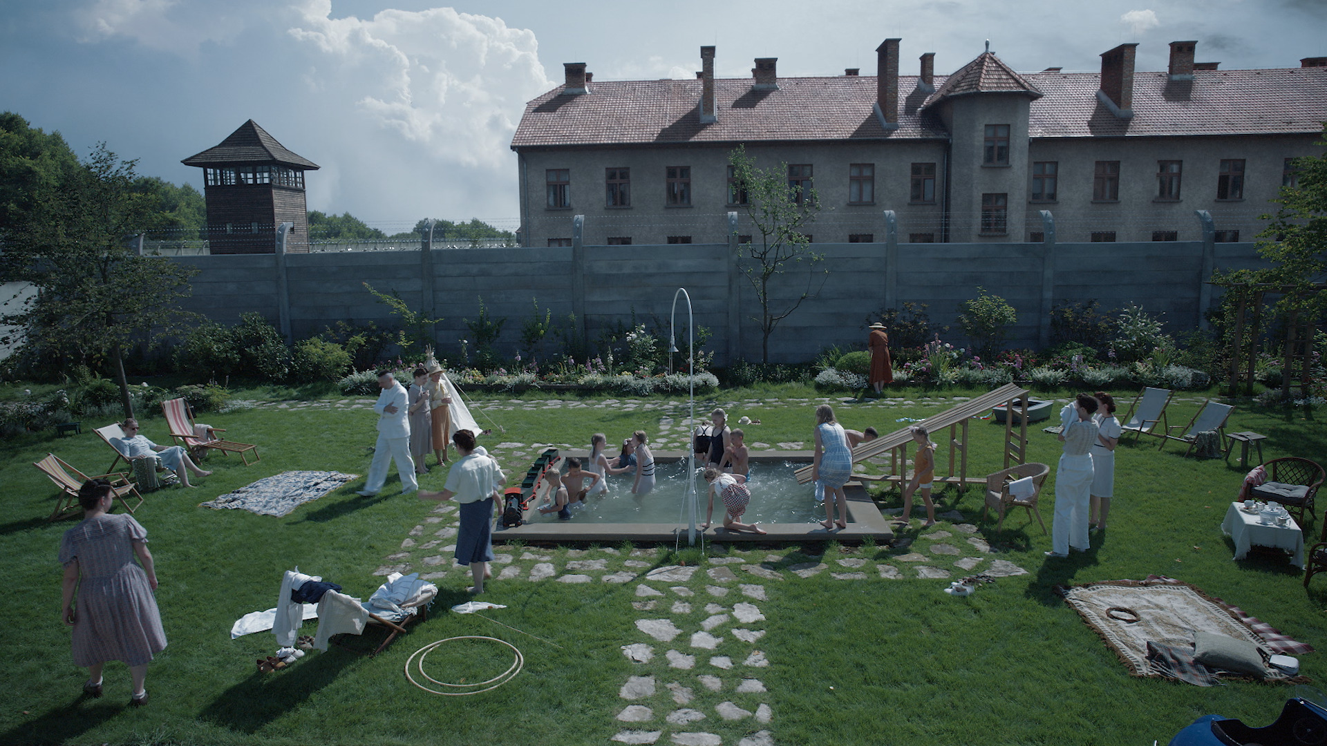 People swim in a pool next to Auschwitz in <em>The Zone of Interest</em>